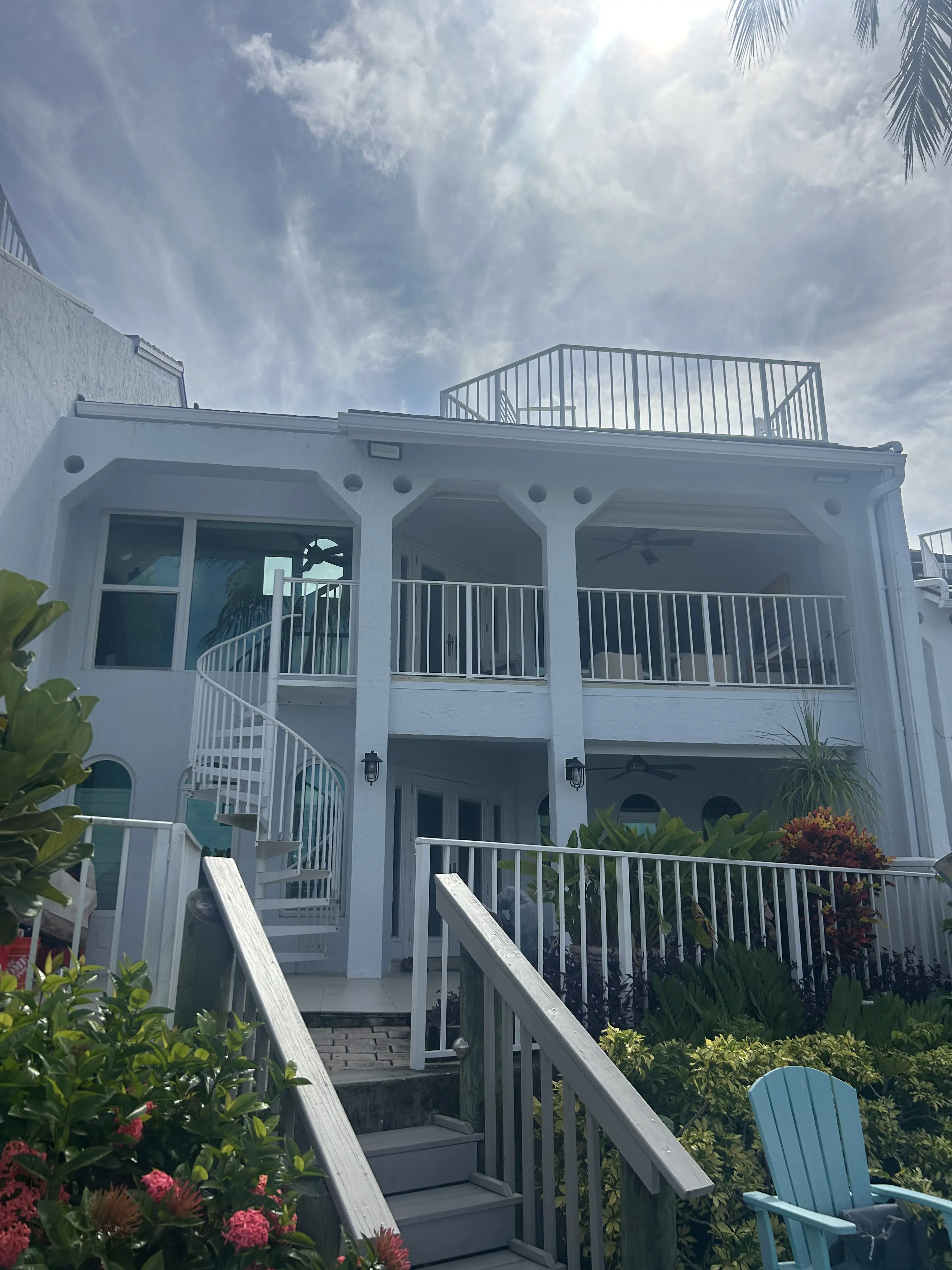 Waterfront condo exterior with clean upper windows and bright white railings